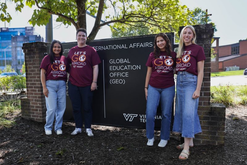 Four students wearing "Go Abroad" T-shirts standing in front of a sign that reads "Global Education Office" 